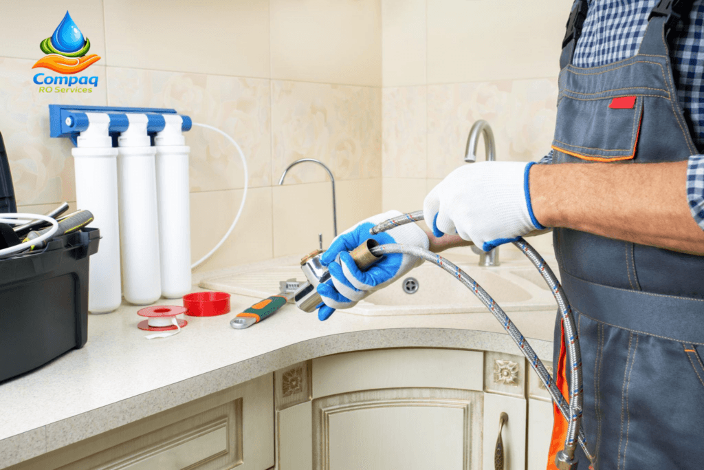 Plumber repair water tap in kitchen. Technician installing reverse osmosis equipment.